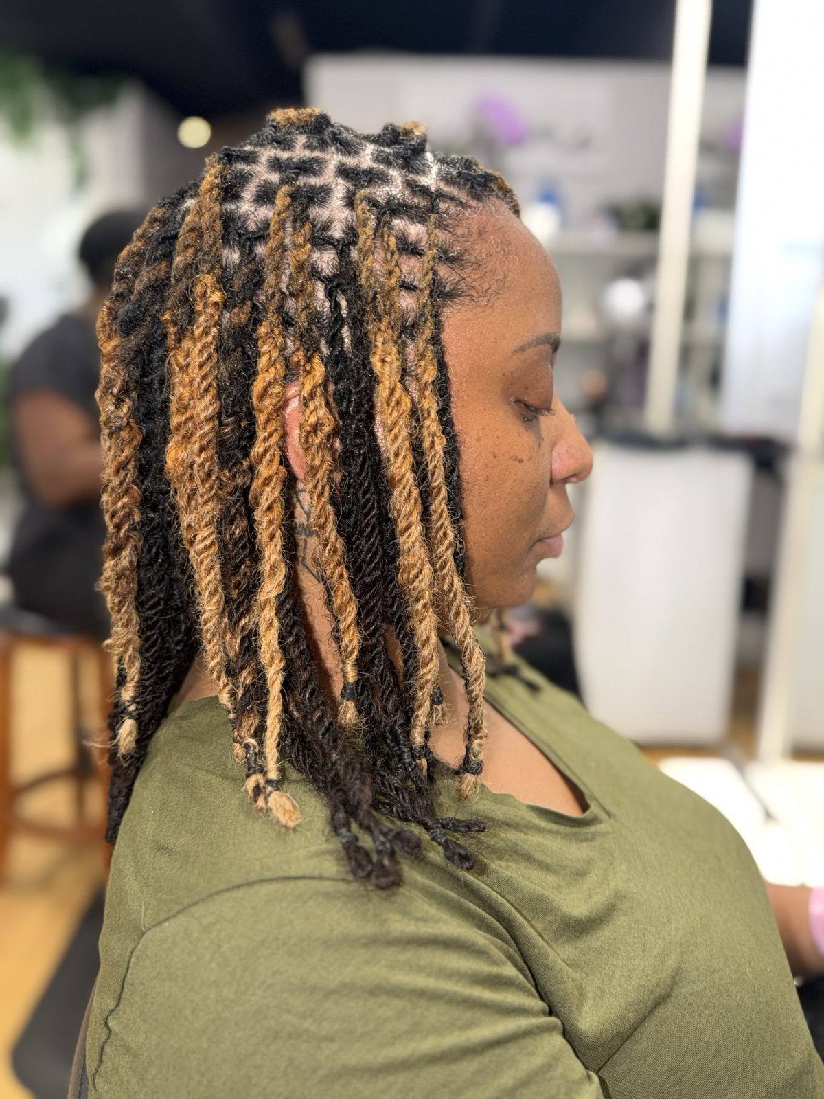 Honey blonde two-strand twists on locs, side view